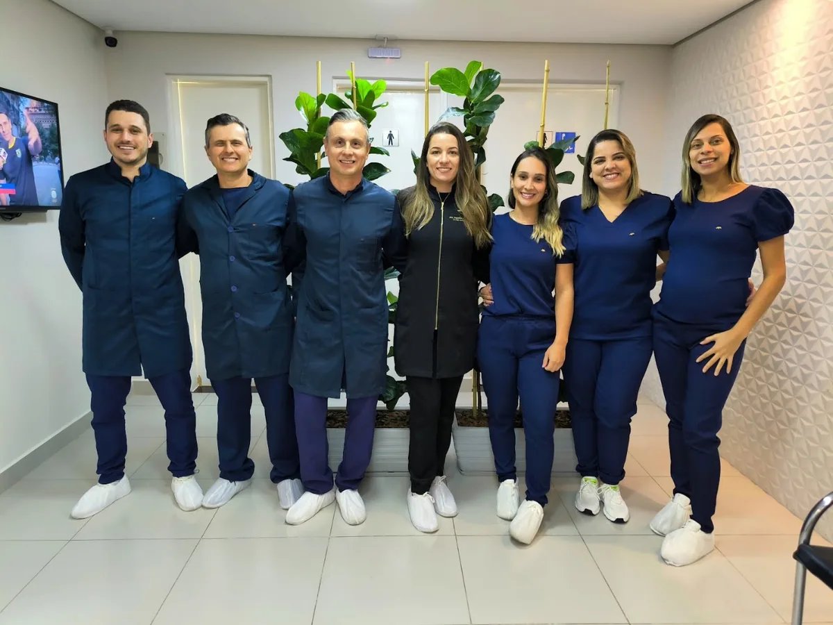 Equipe do consultório sorrindo, uniformizada em azul-marinho
