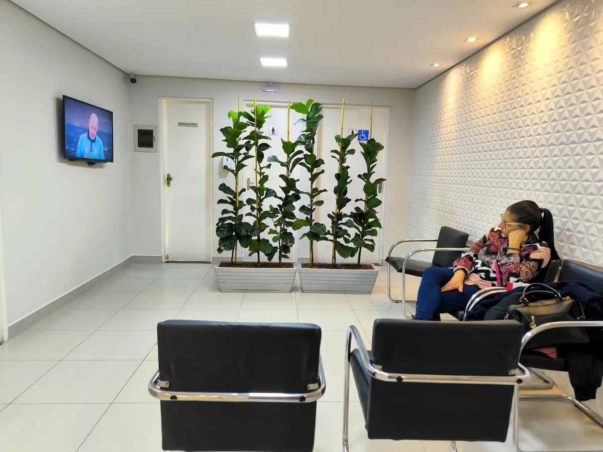 Recepção clara com plantas altas e cadeiras de espera