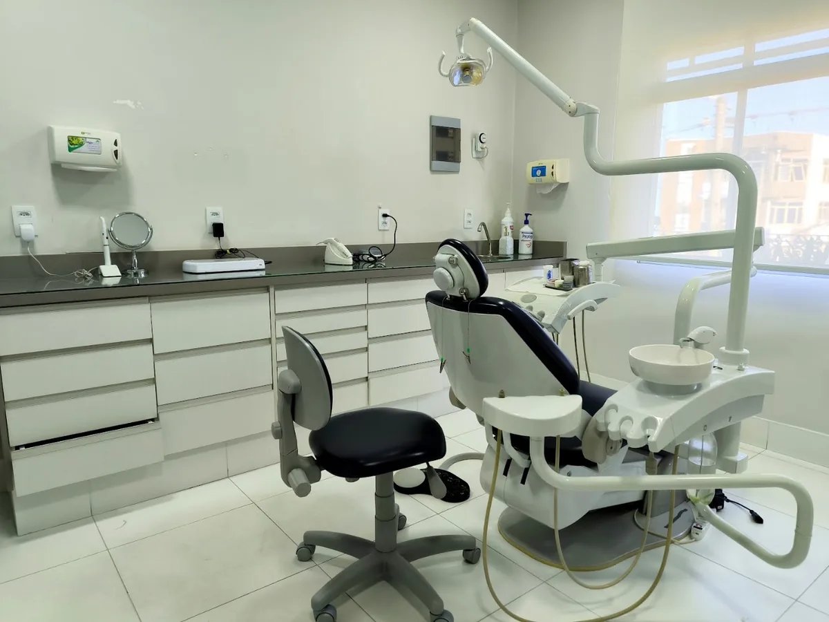 Sala clínica com cadeira odontológica clara e luz natural